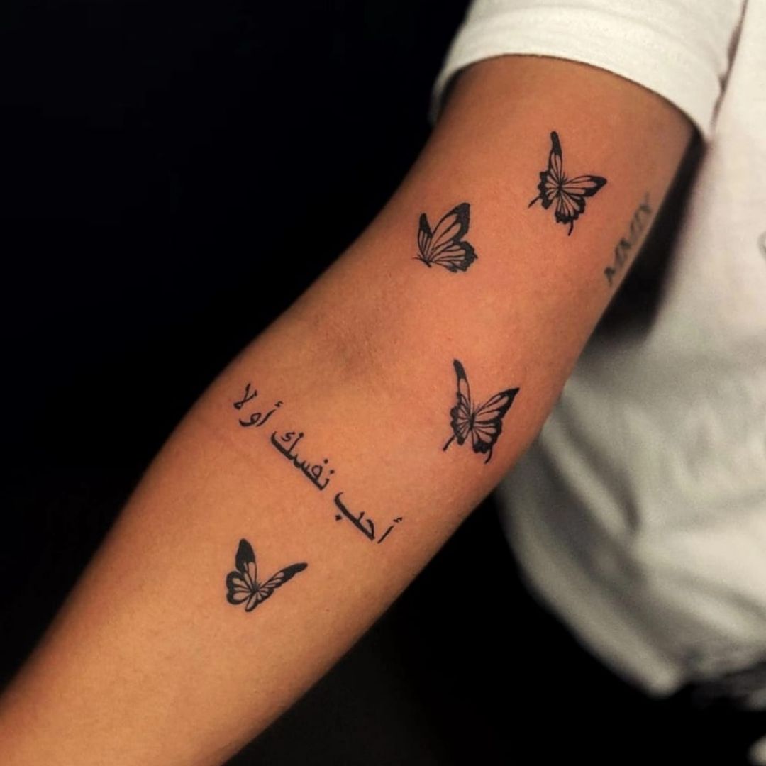 Tattoo artist creating a name tattoo on wrist with professional tattoo equipment.